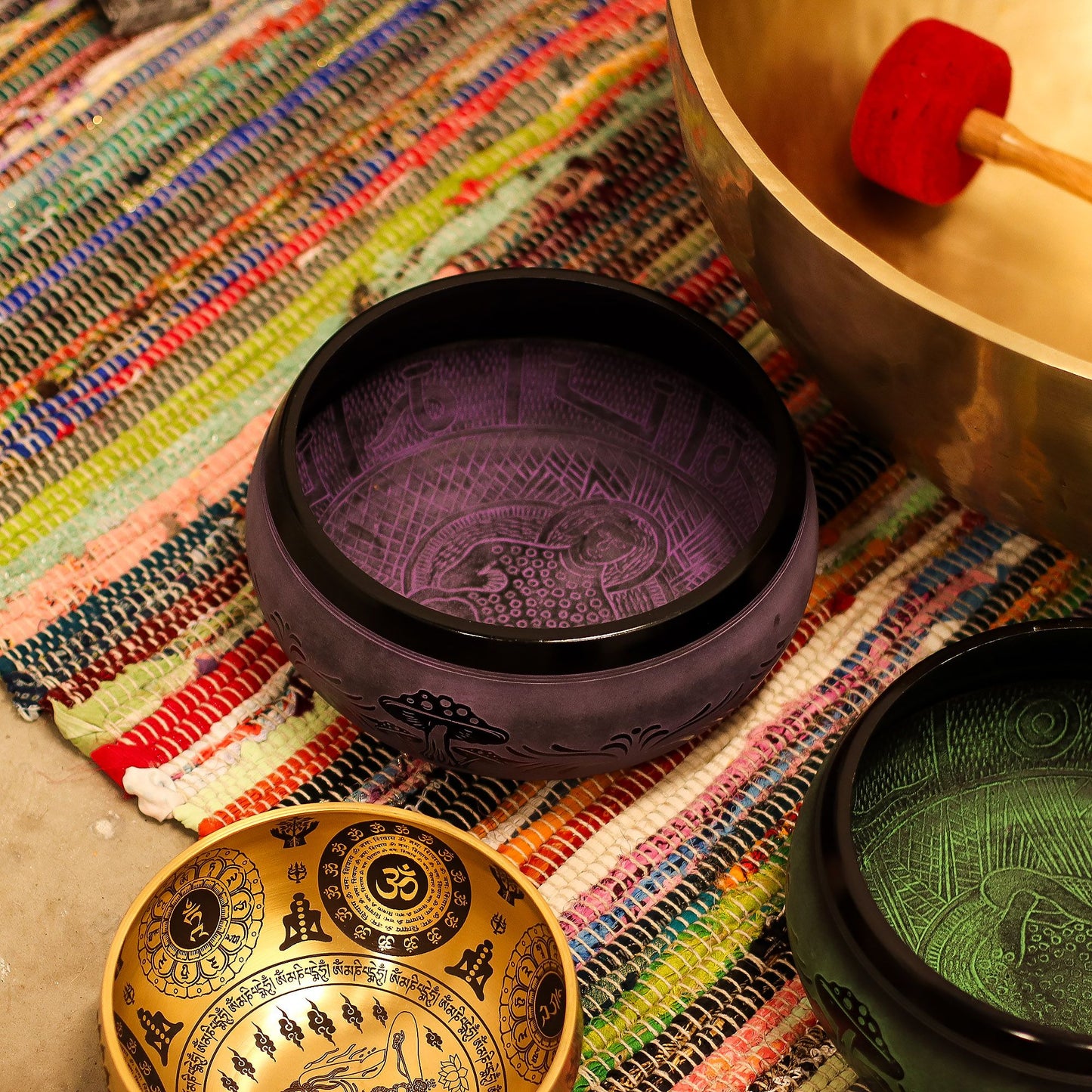 Extra Loud Purple Haze Singing Bowl resting among other beautifully crafted bowls on a vibrant textile, showcasing its intricate design, perfect for meditation and sound therapy - a unique Christmas Gift Home Fragrance.