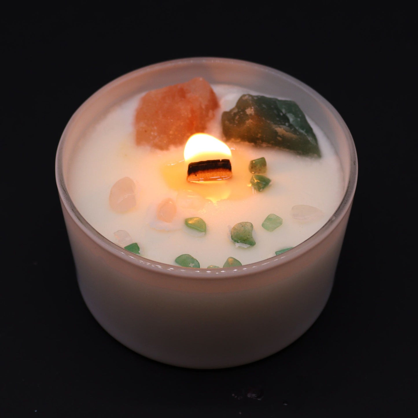 Heart Chakra Rose Musk Candle lit, radiating warm light while revealing the beautiful crystals within. A perfect home fragrance option that makes for a thoughtful Christmas gift.