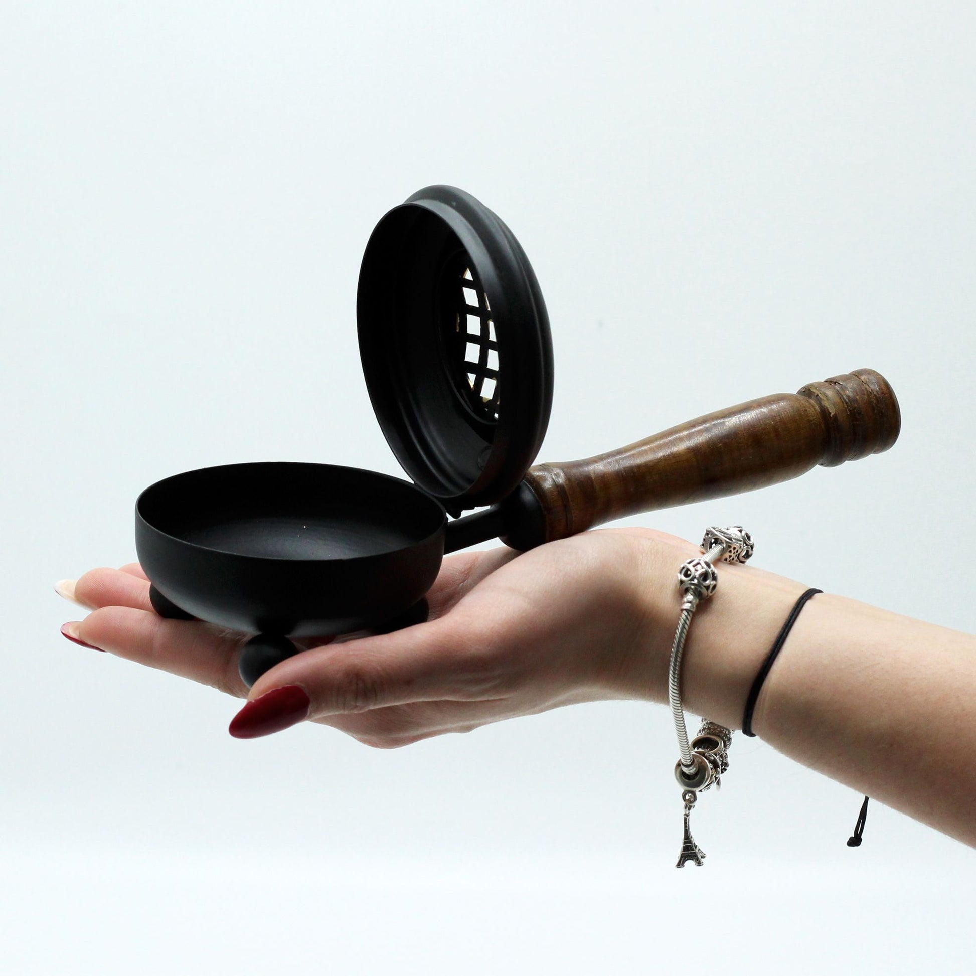 Rustic Cast Iron Incense Burner With Wooden Handle – Gold Accents, held gently in a hand to demonstrate its size and design. An ideal choice for enhancing home fragrance, making it a thoughtful Christmas Gift Home Fragrance.