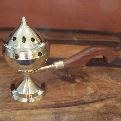 A single elegant brass incense burner featuring a beautifully crafted wooden handle, ready for use in meditation or rituals. This Brass Incense Burner makes a thoughtful Christmas gift for those who appreciate home fragrance.