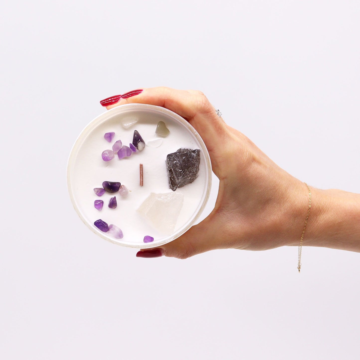 Hand holding Crown Chakra Candle – Ocean Breeze Scent with various gemstones on top, illustrating its calming essence. An excellent Christmas Gift Home Fragrance.