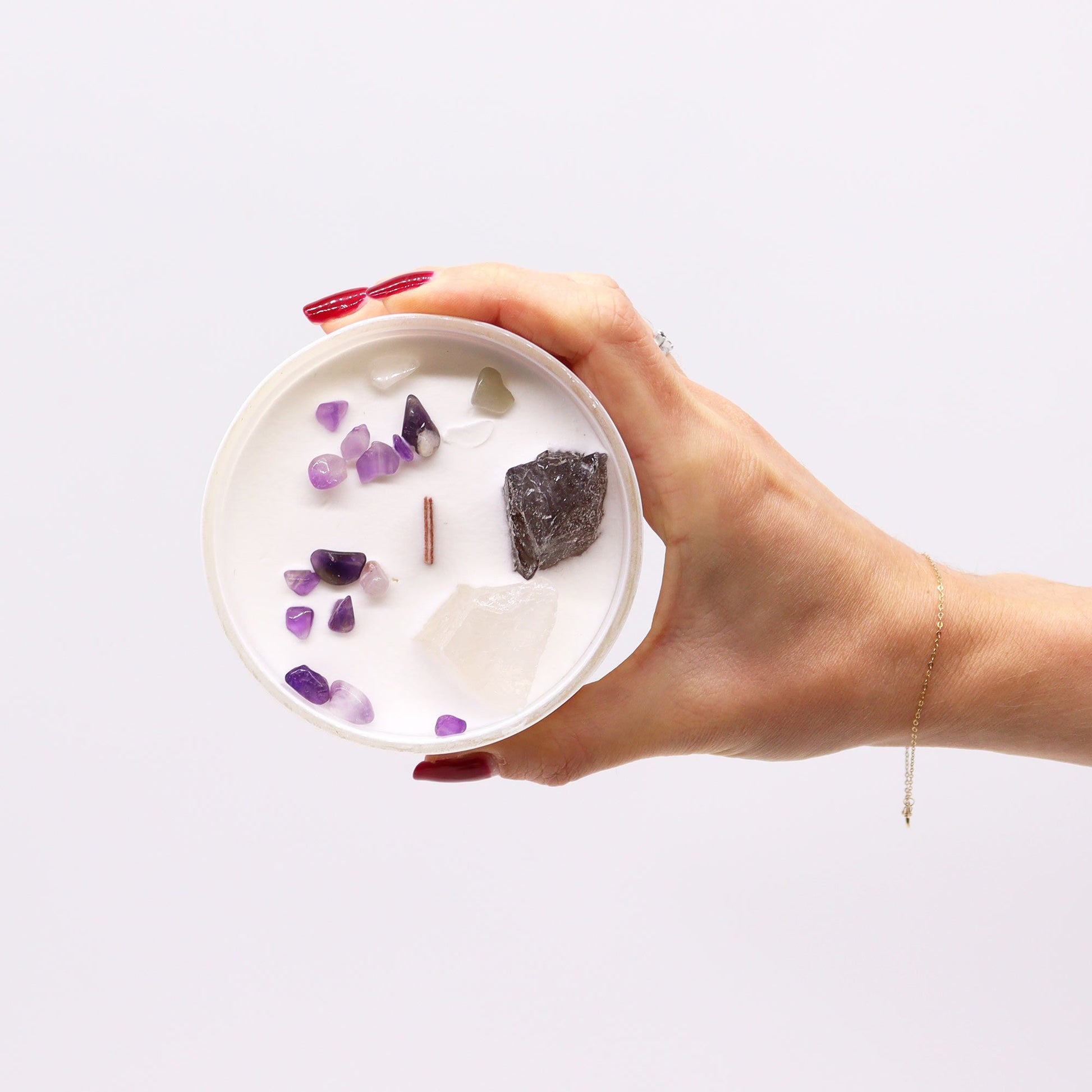 Hand holding Crown Chakra Candle – Ocean Breeze Scent with various gemstones on top, illustrating its calming essence. An excellent Christmas Gift Home Fragrance.
