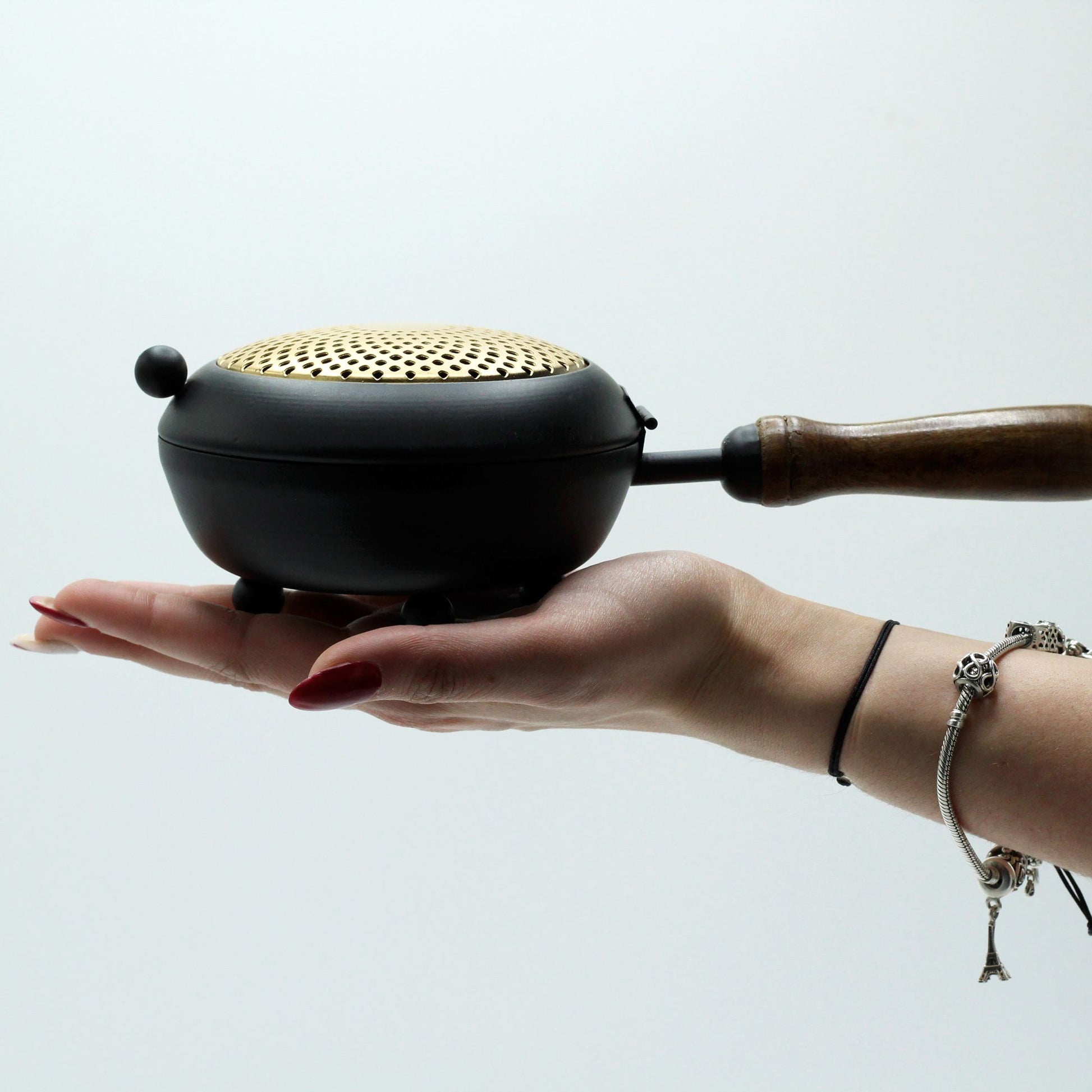 A hand holding the Elegant Large Iron Incense Burner With Gold Accents, showcasing its size and design. Perfect for adding a touch of sophistication to any space, this {{scent}} {{product_type}} – Christmas Gift Home Fragrance is essential for creating a tranquil atmosphere.