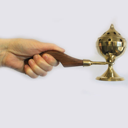 A hand holding an elegant brass incense burner with a wooden handle, showcasing its ergonomic design and usability. This Brass Incense Burner enhances meditation spaces and serves as a unique Christmas gift for home fragrance.