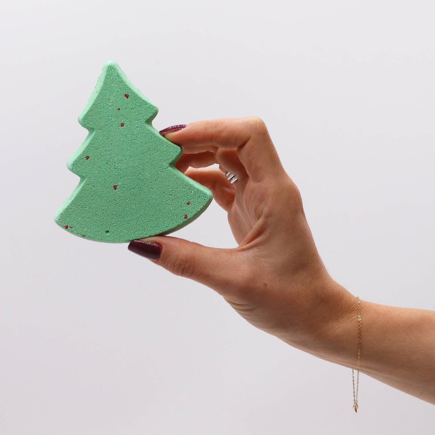 Hand holding a green Christmas tree bath bomb from the Silent Night Christmas Bath Bomb Gift Pack, highlighting its intricate design and festive scent, perfect for a luxurious holiday bath experience. A wonderful Christmas Gift Home Fragrance.