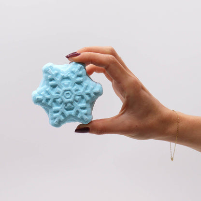 Hand holding a blue snowflake bath bomb from the Break the Ice Christmas Bath Bomb Gift Pack, highlighting its charming details. An excellent option for Christmas gifting and delightful home fragrance.