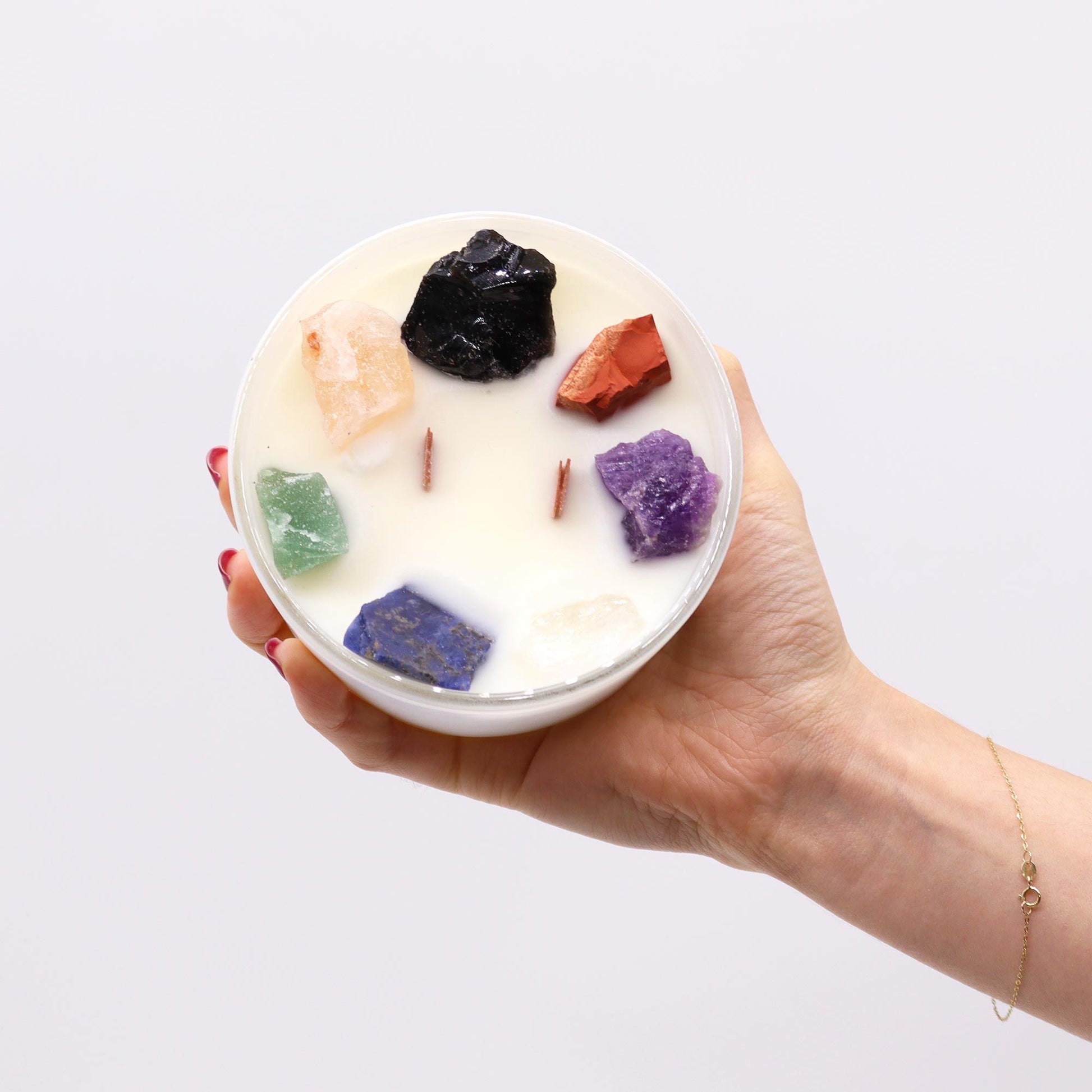 Hand holding the Large Chakra Gemstone Candle - Moon Beams Scent & Light, displaying its beautiful gemstone arrangement, a lovely addition as a Christmas gift home fragrance.