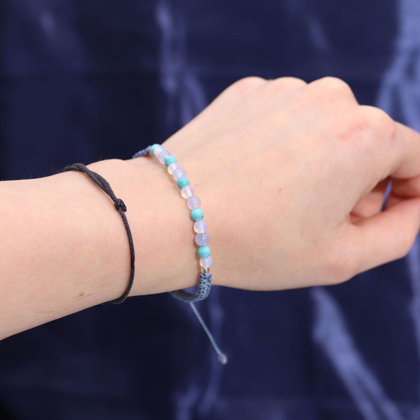 Zodiac Crystal Candle with Gemstone Bracelet - Pisces featuring a close-up of a hand adorned with a beautiful gemstone bracelet alongside a minimalistic black string bracelet. Perfect for enhancing your inner harmony, this set is an ideal Christmas Gift Home Fragrance.