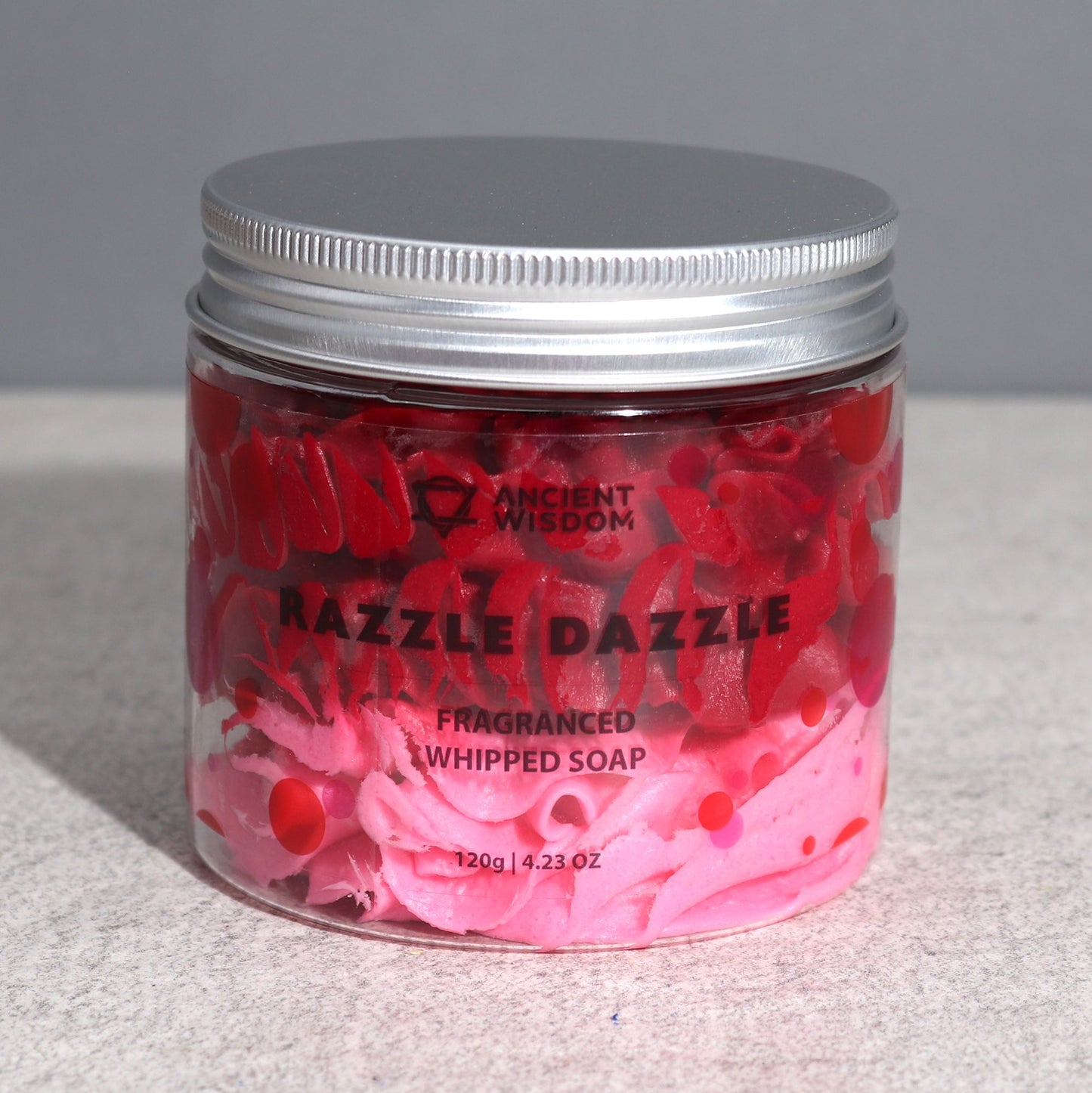 Razzle Dazzle Whipped Soap 120g displayed in a modern setting, featuring bright pink and red swirls in a clear jar, perfect for festive pampering and home fragrance.