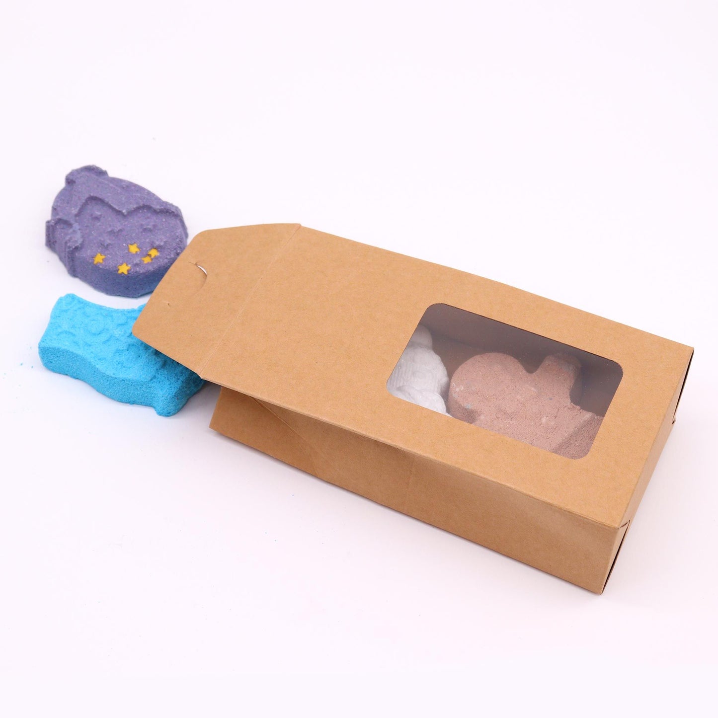 The Christmas Fun Bath Bomb Gift Pack, partially opened, showcasing its delightful contents: a gingerbread bath bomb, snowman bath bomb, ice skate bath bomb, and reindeer bath bomb. Each bath bomb offers unique holiday scents, making it an ideal Christmas gift for those who enjoy home fragrances.