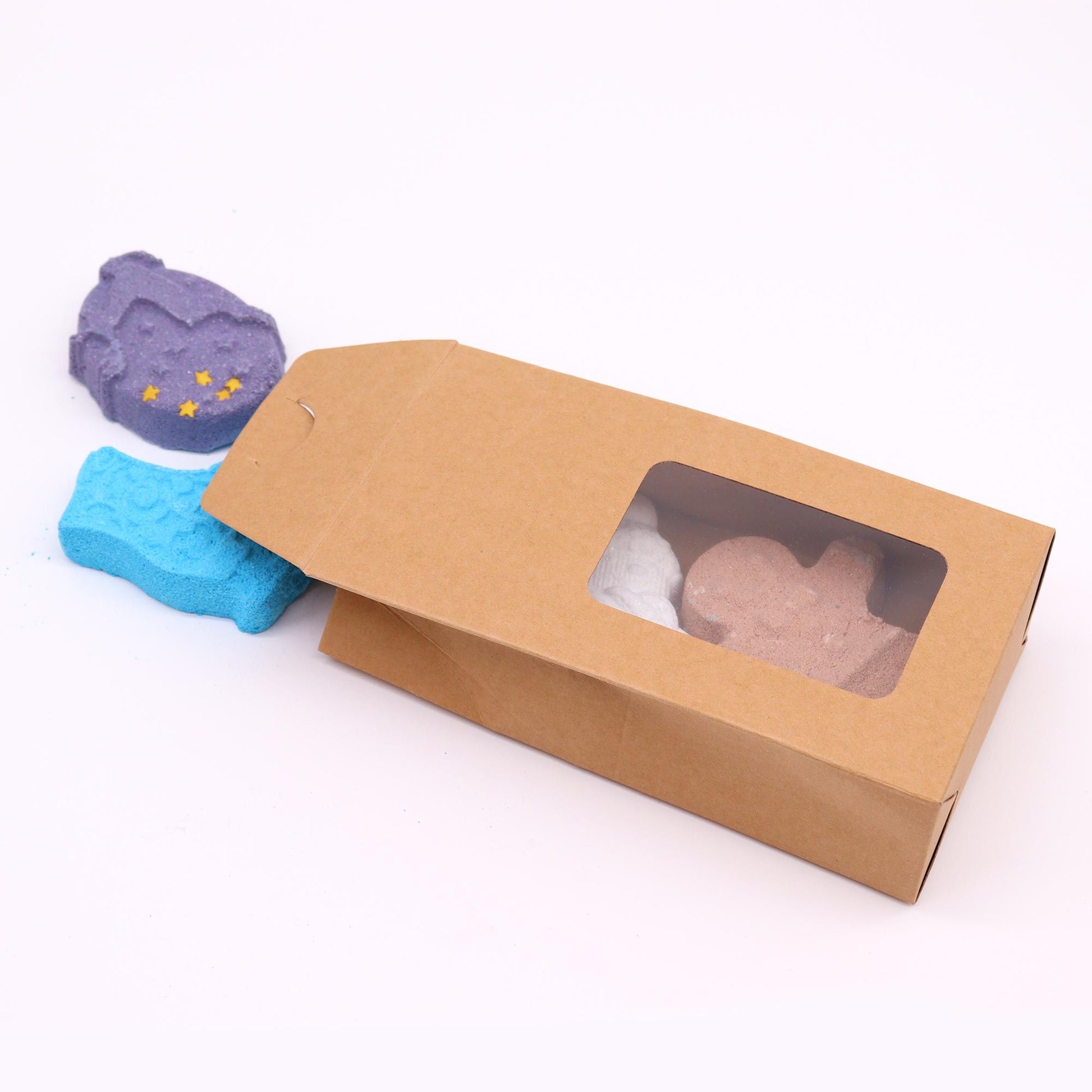 The Christmas Fun Bath Bomb Gift Pack, partially opened, showcasing its delightful contents: a gingerbread bath bomb, snowman bath bomb, ice skate bath bomb, and reindeer bath bomb. Each bath bomb offers unique holiday scents, making it an ideal Christmas gift for those who enjoy home fragrances.