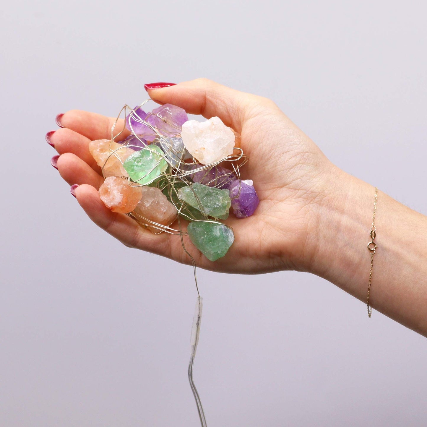 A hand holding a collection of Gemstone Enchantment Lights featuring colourful crystal rocks, perfect for personalised decoration. Great for adding warmth to any space and an excellent choice for Christmas gifts. {{scent}} {{product_type}} – Christmas Gift Home Fragrance.
