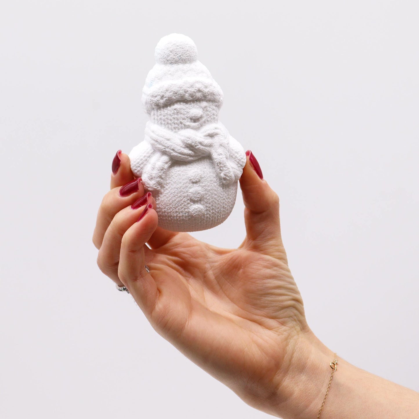 A hand presenting a white snowman bath bomb from the Christmas Fun Bath Bomb Gift Pack. Holly & Ivy scent brings festive cheer, making it a charming addition to holiday self-care routines, a perfect Christmas Gift Home Fragrance.