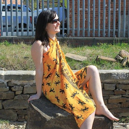 Bali Gecko Sarongs - Yellow 100% Rayon - Summer Fashionable Wraps featuring a woman elegantly draped in an orange sarong with lizard motifs, perfect for beach days and an ideal choice for a thoughtful Christmas gift home fragrance.