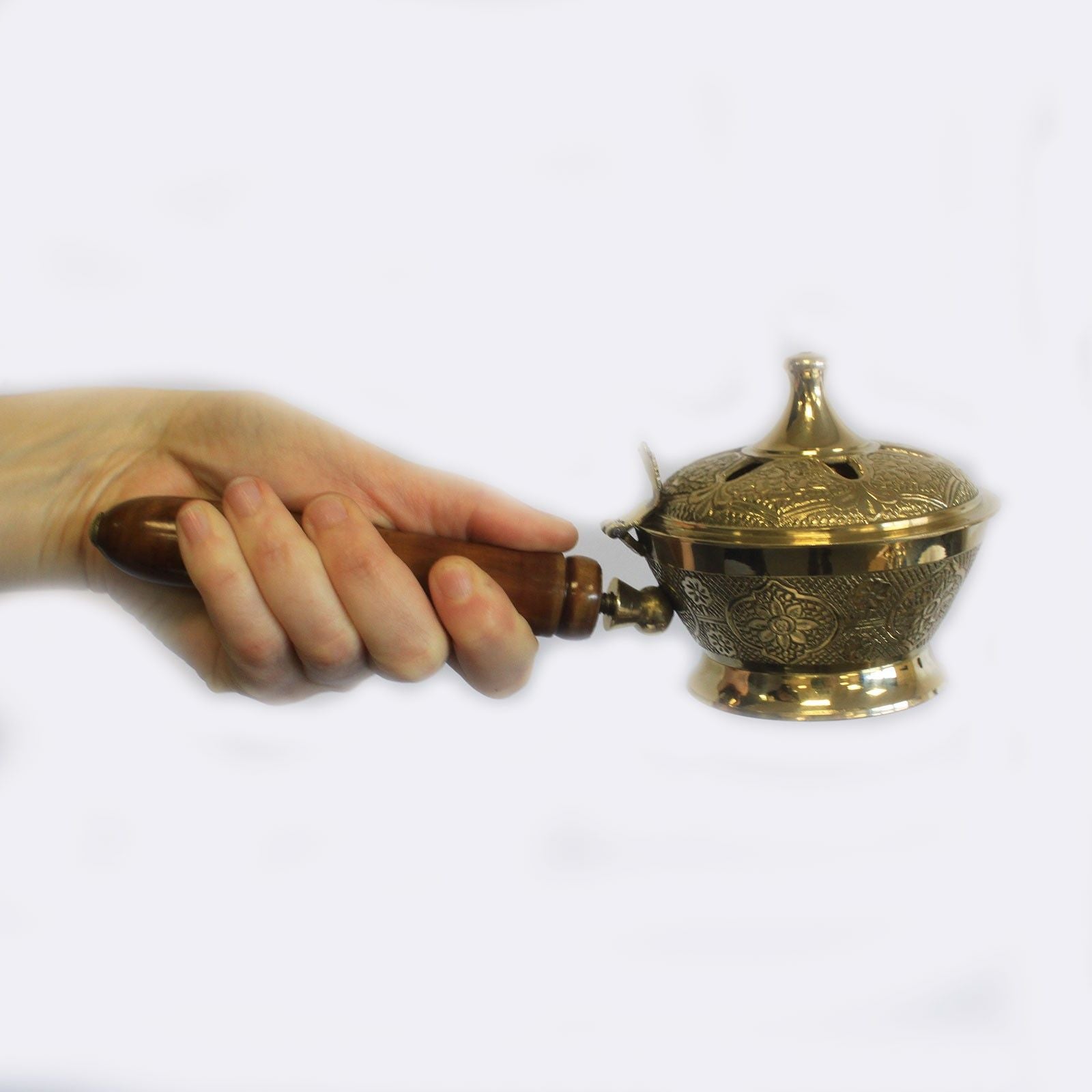A hand holding the Intricate Brass Censer Incense Burner with Wooden Handle, showcasing its ornate floral motifs. This stylish censer is perfect for enhancing home fragrance and makes an ideal Christmas gift for those who appreciate beauty and functionality.