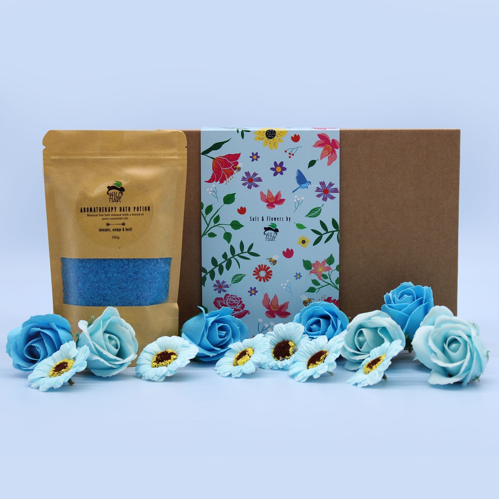 Total Unwind Spa Set - Lavender Bath Salt & Soap Flowers displayed with a golden pouch of lavender bath salt and elegant blue soap flowers. Perfect for a Christmas gift home fragrance.