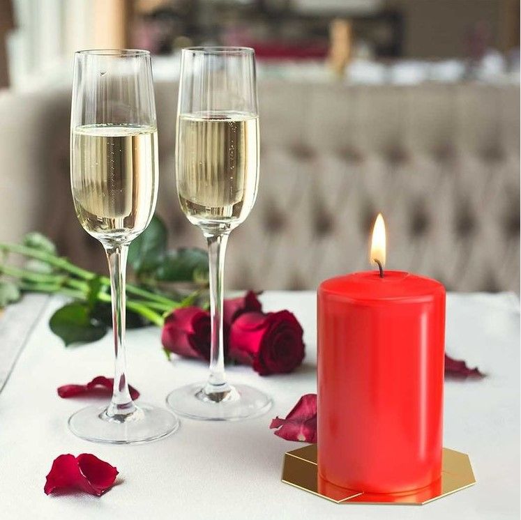 An inviting setup showcasing a Red Pillar Candle 50mm x 100mm – 20 Hour Cozy Burn, surrounded by two glasses of champagne and red rose petals. Ideal for festive occasions, this {{scent}} {{product_type}} serves as a wonderful Christmas gift, bringing a cozy ambiance to any space.