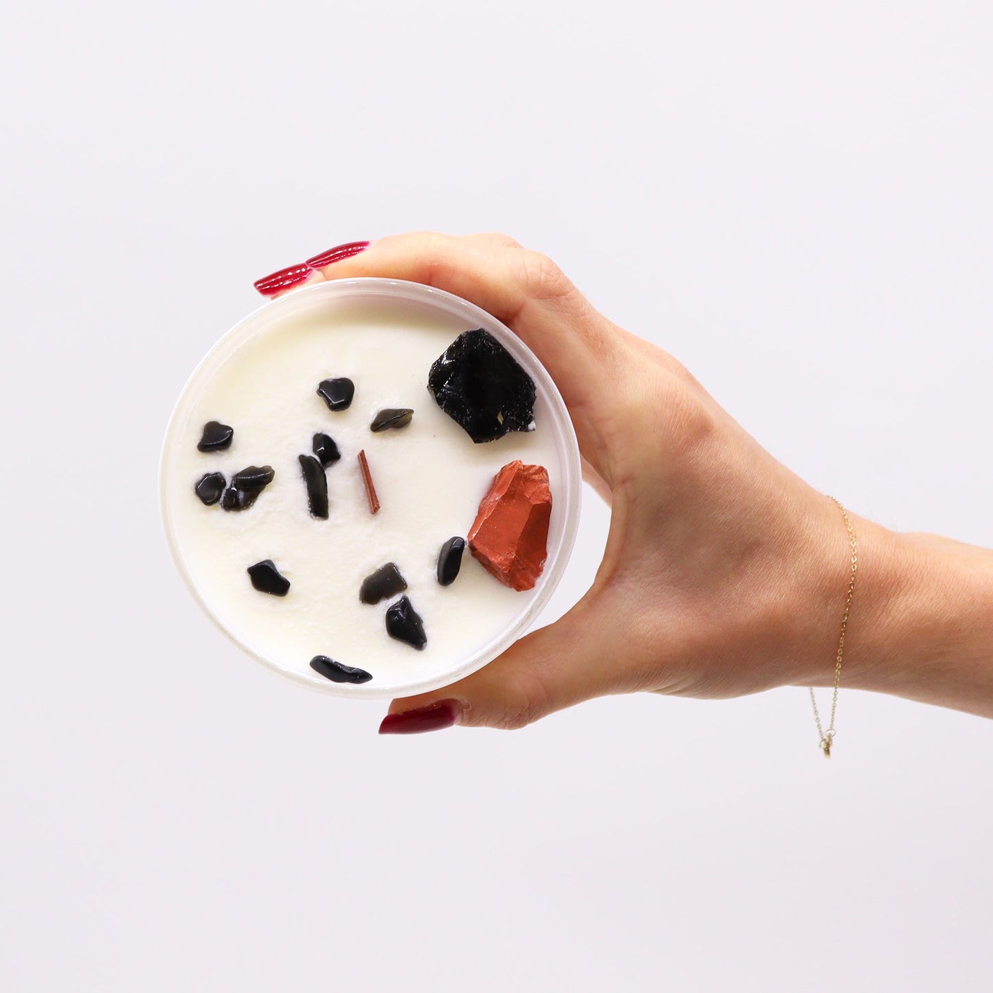 Root Chakra Crystal Candle - Black Oud Scent with Gemstones held in hand, featuring black and red gemstones, perfect for creating a serene atmosphere. Ideal for Christmas Gift Home Fragrance.