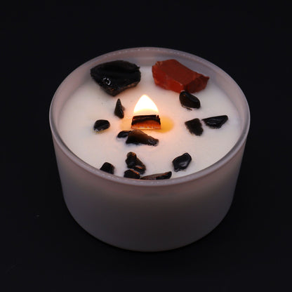 Root Chakra Crystal Candle - Black Oud Scent with Gemstones burning softly, showcasing black and red gemstones on top. A beautiful addition for a relaxing environment and a great Christmas Gift Home Fragrance.