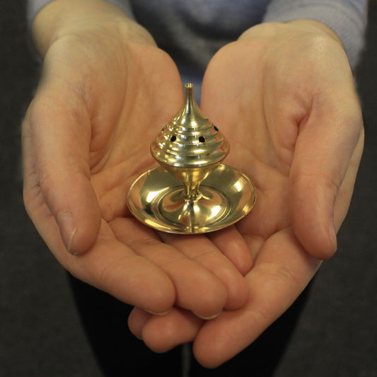 A person holding a Small Brass Incense Burner with an elegant design for meditation. This beautiful burner enhances the ambience for any meditation space and is perfect as a Christmas gift for home fragrance enthusiasts.