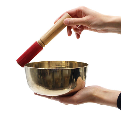 A person holding a Brass Singing Bowl 17Cm, showcasing its shiny surface and wooden mallet, perfect as a mindful meditation tool for relaxation – ideal Christmas gift for home fragrance lovers.