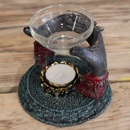 Antique Buddha Oil Burner captured beautifully in a rustic setting, with hands supporting a glass container. This elegant decor piece is perfect for enhancing the soothing atmosphere in your home, making it a thoughtful Christmas gift filled with home fragrance.