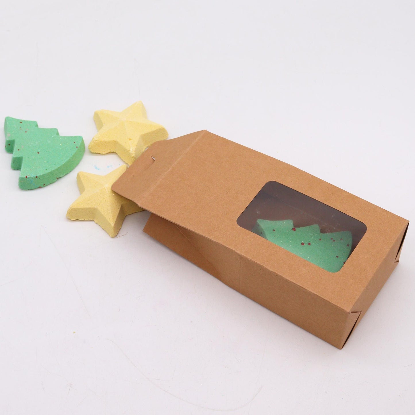 Chocolate brown cardboard box containing two green Christmas tree bath bombs and two yellow star bath bombs, highlighting the charm of the Silent Night Christmas Bath Bomb Gift Pack for a unique Christmas Gift Home Fragrance.