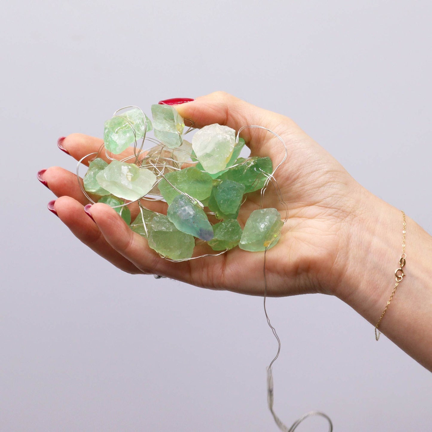 A hand holding Crystal Jade Gemstone Enchantment Lights - 20 LED Rock Strings, showcasing stunning green crystal rocks that create a warm festive glow, perfect for adding charm to your decor. Ideal as a Christmas gift for home fragrance enthusiasts.