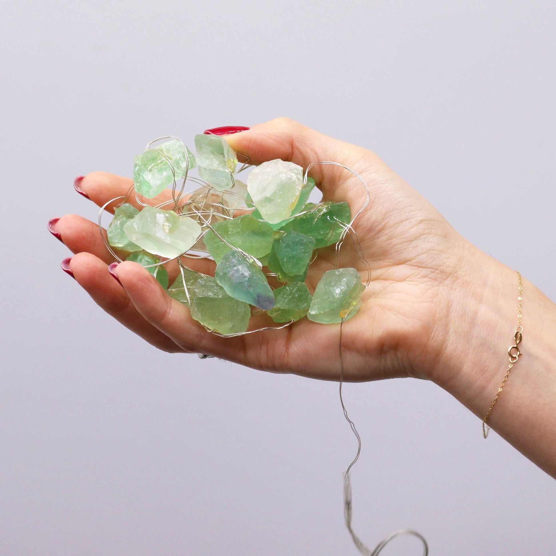 A hand holding Crystal Jade Gemstone Enchantment Lights - 20 LED Rock Strings, showcasing stunning green crystal rocks that create a warm festive glow, perfect for adding charm to your decor. Ideal as a Christmas gift for home fragrance enthusiasts.