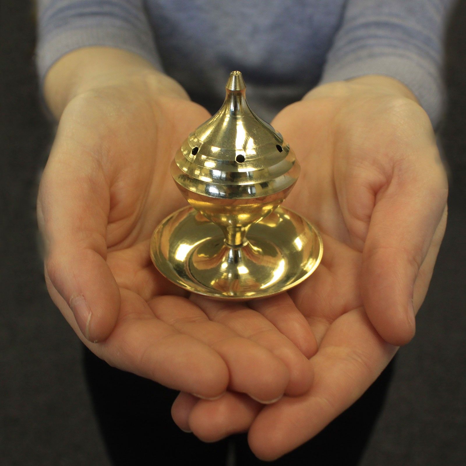 A hand holding the Elegant Medium Brass Incense Burner, demonstrating its compact size and elegant design. Perfect for rituals and meditation, this burner brings warmth and fragrance to any space, making it an excellent {{scent}} {{product_type}} – Christmas Gift Home Fragrance.