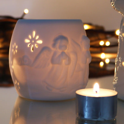 Elegant Cherubs Design Ceramic Oil Burners casting a warm glow with a candle nearby. These beautiful pieces are perfect for setting a tranquil mood at home and are wonderful as Christmas gifts for fragrance fans.