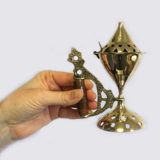 Elegant Brass Cone Incense Burner With Wooden Handle showcased in a hand, perfect for rituals. Ideal for creating a warm ambiance during aromatherapy, this exquisite burner makes a thoughtful Christmas gift for home fragrance enthusiasts.