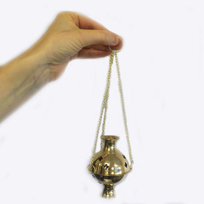 A hand holding a Hanging Brass Incense Burner, ideal for meditation and rituals. This beautiful incense burner is perfect for creating a serene atmosphere and makes a thoughtful Christmas gift. Enhance your home fragrance with this stylish scent product – Christmas Gift Home Fragrance.