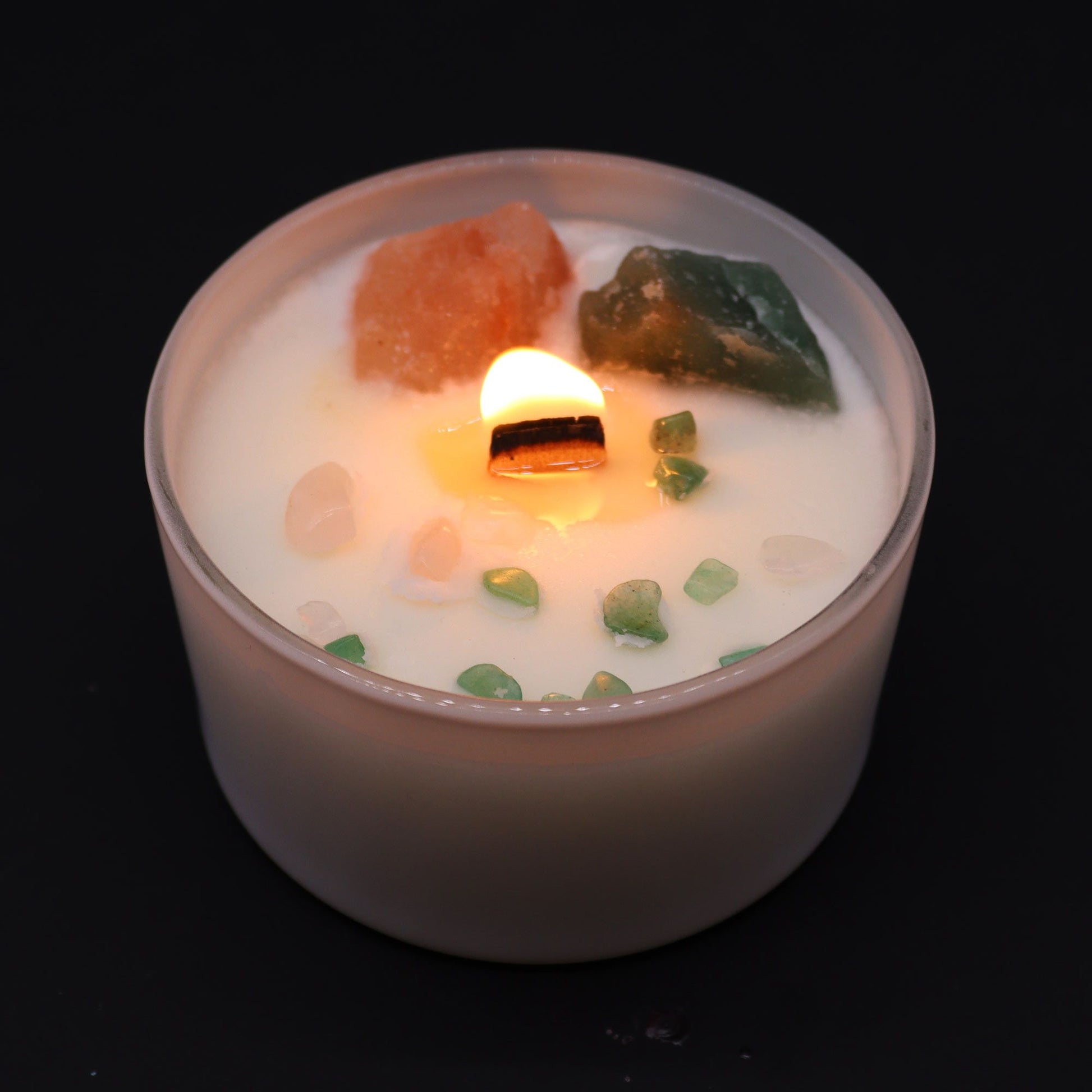 Heart Chakra Rose Musk Candle lit, radiating warm light while revealing the beautiful crystals within. A perfect home fragrance option that makes for a thoughtful Christmas gift.