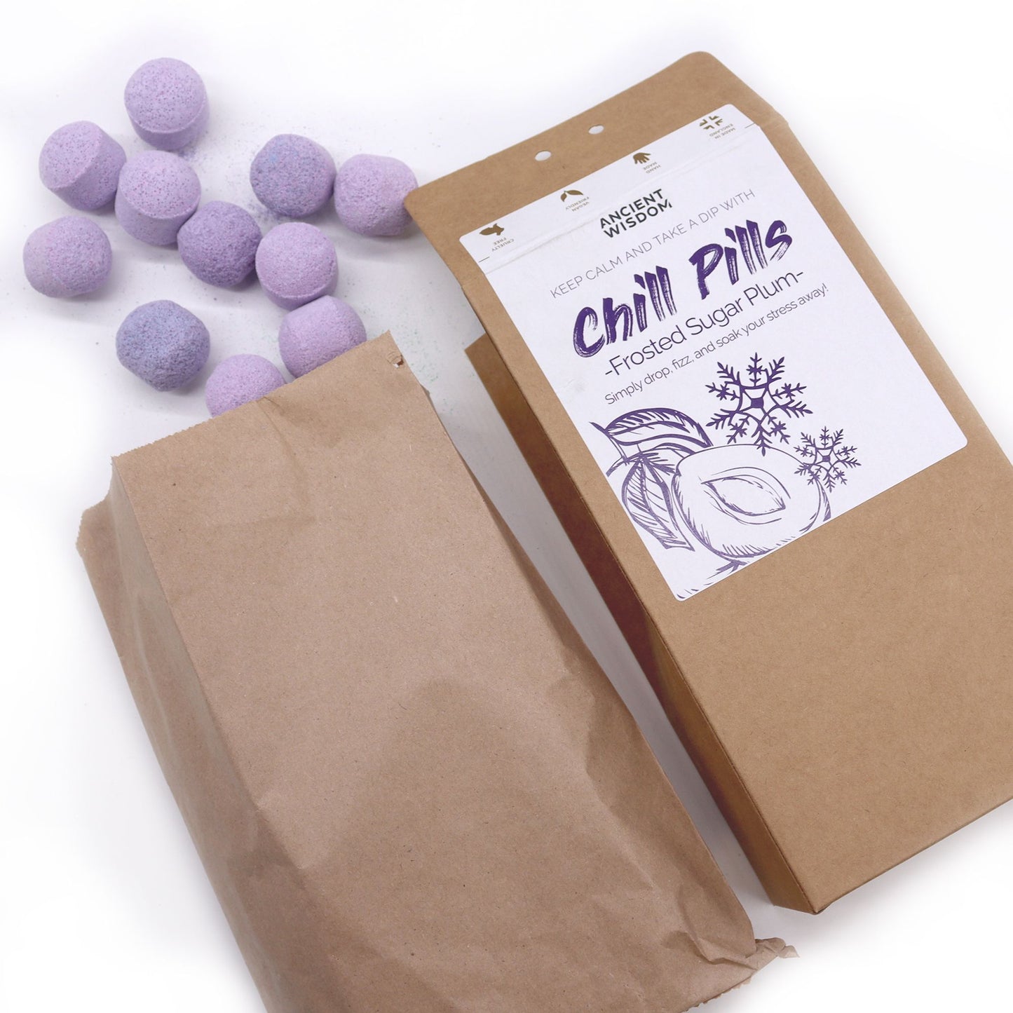 Open package of Frosted Sugar Plum Chill Pills with scattered purple mini bath bombs, an enchanting addition to any holiday self-care routine. A perfect Christmas gift for home fragrance.