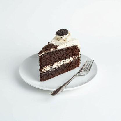 Slice of chocolate cake with cream and an Oreo cookie on a white plate with a fork.